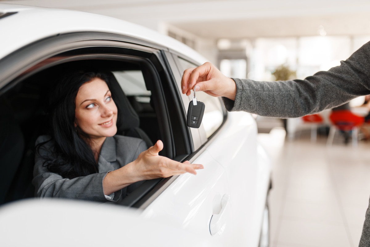 une-femme-heureuse-prend-la-cle-dune-nouvelle-voiture-dans-la-salle-dexposition